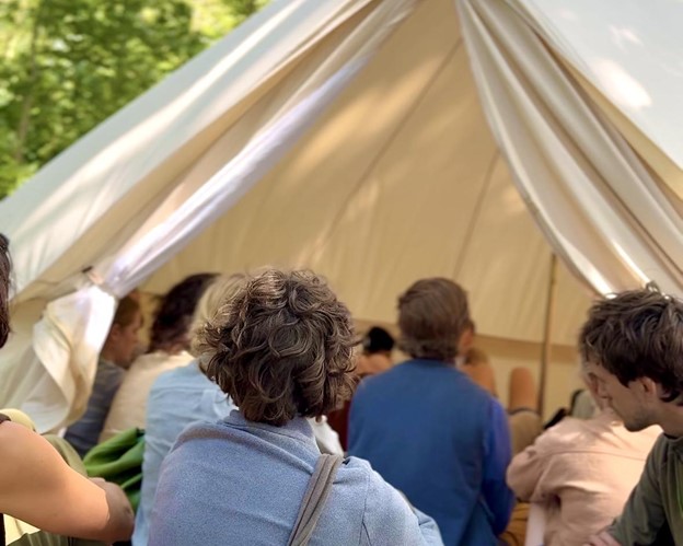 Participants gather inside and outside the entrance to the bell tent to listen to the sounds of soil and the research being done by the facilitators.